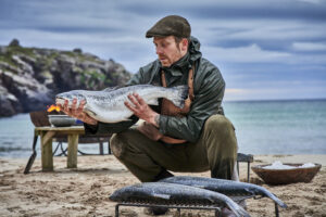 man holding fresh salmon on beach